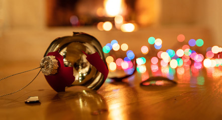 Christmas ornament broken, colorful lights glowing, blur burning fireplace background