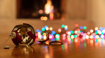 Christmas ball broken, colorful lights glowing, blur burning fireplace background