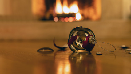 Christmas ball broken, blur burning fireplace background