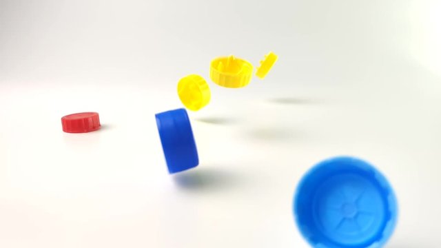 colored plastic lids fall on the table on a white background. colored plastic caps recycling