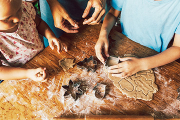 Joint family cooking of festive Christmas gingerbread in the kitchen. Children help mom.