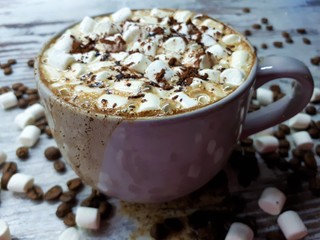  close-up of a hot drink, a cup of coffee / cocoa with marshmallows and chocolate chips on an abstract wooden surface background