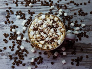  close-up of a hot drink, a cup of coffee / cocoa with marshmallows and chocolate chips on an abstract wooden surface background