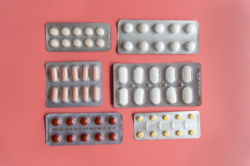 different blisters with tablets on pink background