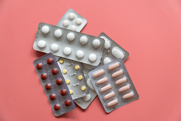 different blisterspackages with tablets on pink background