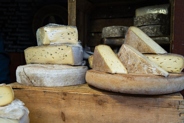 Cantal or saint nectaire french mature morbier cheese on the wooden shelf stored for sale or use organic food market