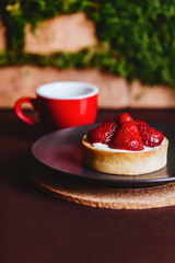 Coffee in a red cup with biscuit cookies on a rustic wooden board