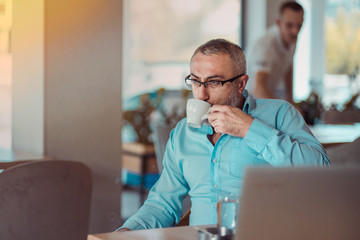 Middle aged man drinking first morning coffee on his job break in a cafe.