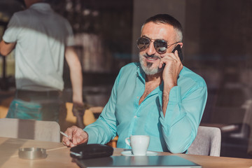 Middle aged man talking on the phone on his job break in a cafe. Business people