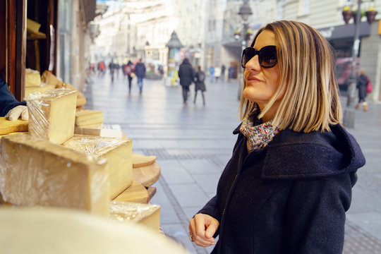 Fototapeta Portrait of caucasian woman female tasting and buying organic french cheese on the street market sail saint nectaire or brie in winter or autumn day in europe or america