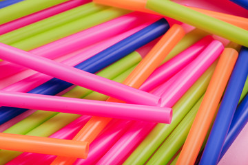 colored tubules for juice and cocktails on pink background. Colorful drink straws. straw, plastic free, reusable plastic drinking background, plastic free. Plastic pollution concept.