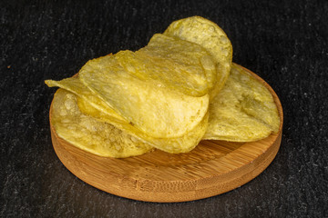 Lot of whole crisp potato chip on round bamboo coaster on grey stone