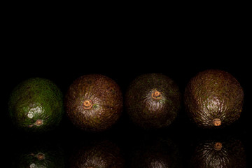 Group of four whole fresh green avocado isolated on black glass