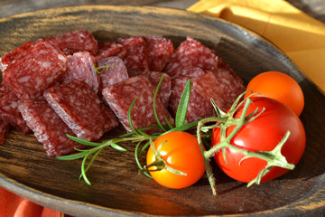 Dry sausage and Italian salami on raw wooden cutting board close up