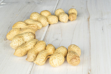 Lot of whole tasty beige peanut on white wood
