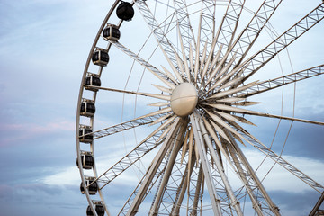 large Ferris wheel on the background of cloudy clouds in the amusement park. 