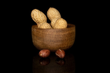 Group of two whole two pieces of tasty beige peanut in bamboo bowl isolated on black glass