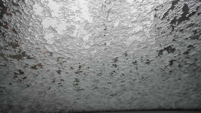 rain and icy snow on car windshield during winter day
