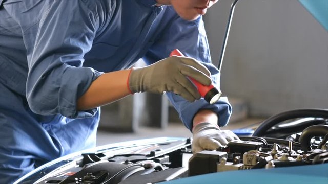 Asian Man mechanic inspection Shine a torch car engine checking bug in engine.Blue car for service maintenance insurance with car engine.for transport automobile automotive video clip