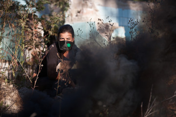 woman in a gas mask out of the house, from which goes smoke
