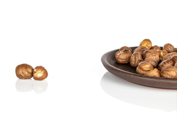 Lot of whole tasty brown hazelnut with brown ceramic coaster isolated on white background