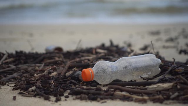 4k Video of a trash empty bottle on sand beach social enviroment global issue.