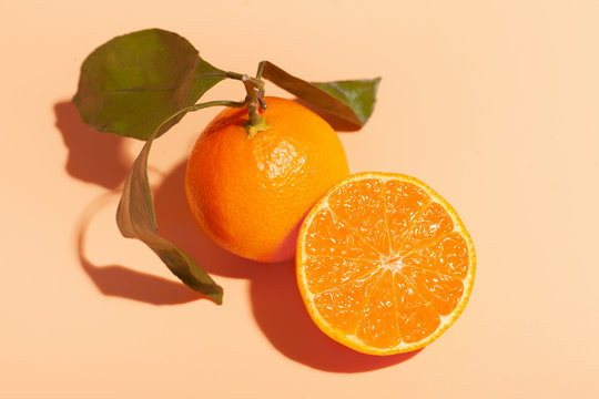 ripe orange tangerine near cutted juicy half mandarin isolated on orange background