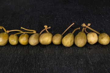 Lot of whole pickled green caper line on grey stone