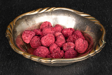 Lot of whole dried raspberry in copper bowl on grey stone
