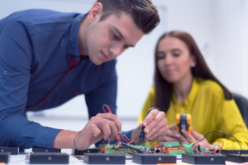 Two young handsome engineers working on electronics components.Tech tests electronic equipment in service center. Technologically Advanced Scientific Research Center.