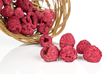 Lot of whole dried raspberry in round rattan bowl isolated on white background