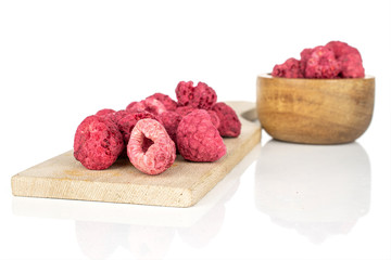 Lot of whole dried raspberry in bamboo bowl on wooden cutting board isolated on white background