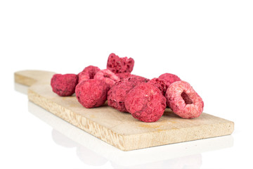 Lot of whole dried raspberry on wooden cutting board isolated on white background