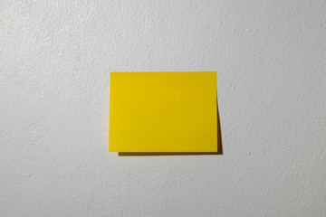 yellow post it note in the white cement wallpaper.  