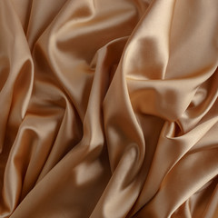 Wavy gold silk, atlas or veil fabric, crumpled with creases, bended in spiral wrinkle