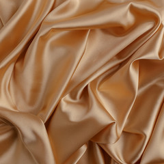 Wavy gold silk, atlas or veil fabric, crumpled with creases, bended in spiral wrinkle