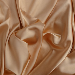 Wavy gold silk, atlas or veil fabric, crumpled with creases, bended in spiral wrinkle