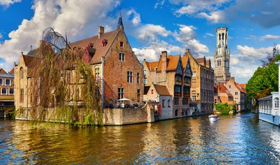 Fototapeten Brügge, Belgien. Alte mittelalterliche europäische Stadt. Blick auf den Turm Belfort van Brugge und das alte Gebäude am Ufer des Kanals Rozenhoedkaai. Panoramablick mit blauem Himmel und Wolken. Berühmter Tourist. © Yasonya
