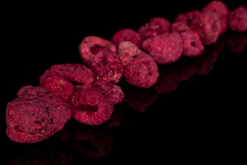 Lot of whole dried raspberry diagonal isolated on black glass
