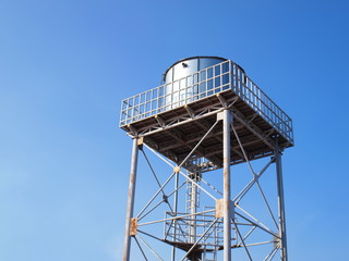 Silver water tank on the tower On a clean blue sky background With copy space
