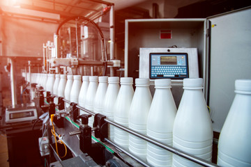 White plastic milk bottles on the conveyor on a modern dairy plant