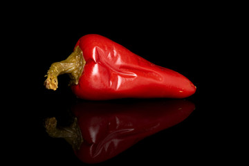 One whole pickled red pepper isolated on black glass