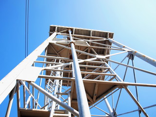 White metal tower structure On a background of clean blue sky and electricity lines