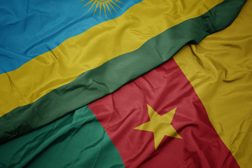 waving colorful flag of cameroon and national flag of rwanda.