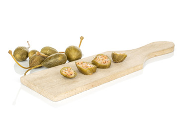 Group of lot of whole four slices of pickled green caper on wooden cutting board isolated on white background