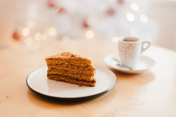 Italian coffee Cup and honey cake on the table near the Christmas tree with white bokeh