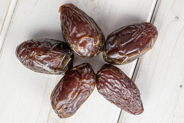 Group of five whole dried brown date fruit star flatlay on white wood