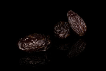 Group of three whole dried brown date fruit isolated on black glass