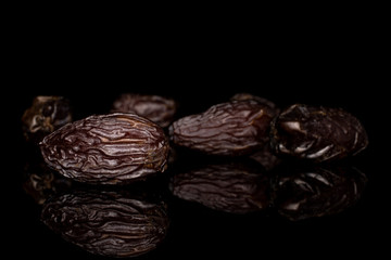 Group of five whole dried brown date fruit isolated on black glass