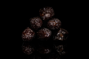 Group of six whole dried brown date fruit isolated on black glass